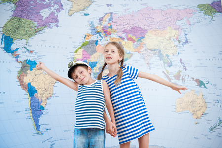 two cute kids in striped sailor shirts on world map backgroundの写真素材