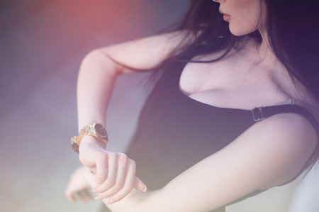 girl checking time by looking at an expensive gold watch on her wrist hand