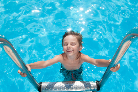 happy healthy little boy smiling in summer outdoor swimming azure pool vacationの写真素材