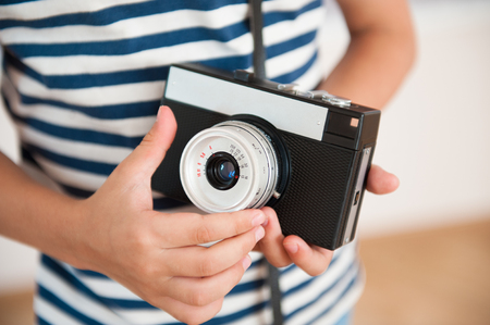 closeup of little kid wearing striped shirt with hands holding vintage cameraの写真素材