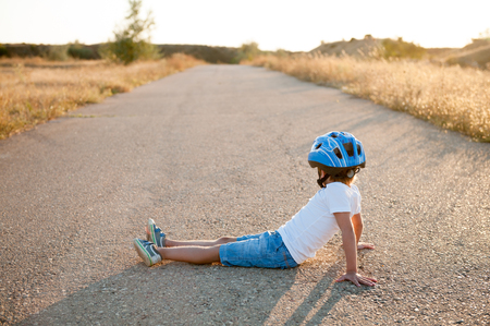 little boy in sport helmet sitting on empty highway road looking in to future conceptの写真素材