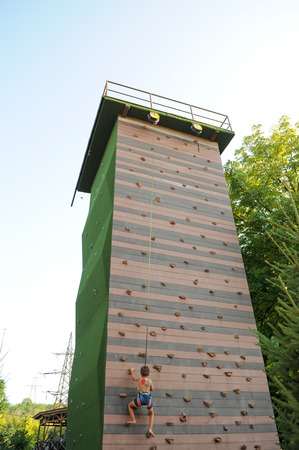 little caucasian boy climbing rock wall outdoor. Concept of sport life.の写真素材