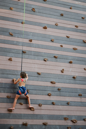 little kid climbing rock wall outdoors in amusement sport parkの写真素材