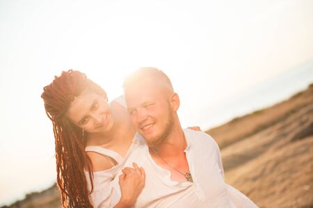 happy young smiling loving nordic man and arabic woman with dreadlocks on summer sunsetの写真素材