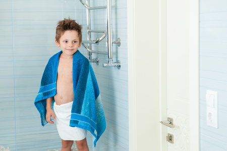 cute healthy little caucasian boy with blue towel in bright bathroomの写真素材