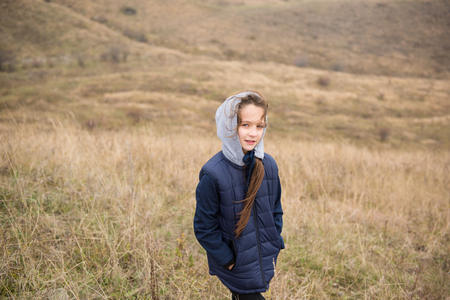 sport cute caucasian little girl in jacket with hood in windy mountains during hikingの写真素材