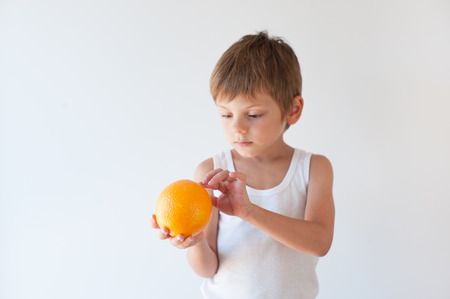 healthy small kid in white shirt holding orange fruit on white backgroundの写真素材