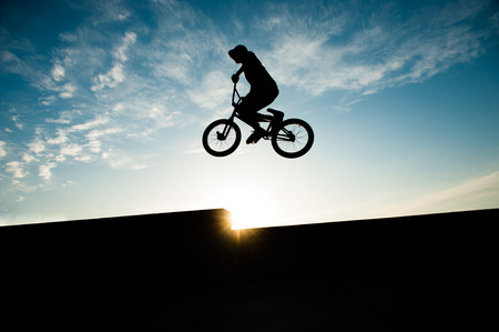 extreme jumping high rider on bicycle flying on beautiful sky sunset backdrop in Californiaの写真素材
