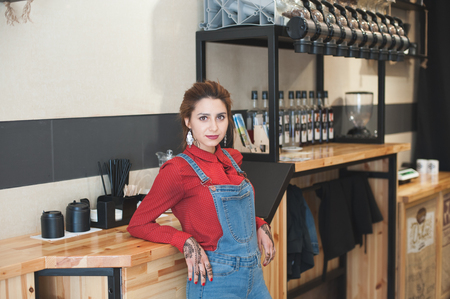 beautiful modern trendy young caucasian girl in red shirt and denim suit in coffee shopの写真素材