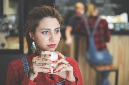 beautiful young caucasian female with glass of coffee espresso cappuccino in coffeehouseの写真素材