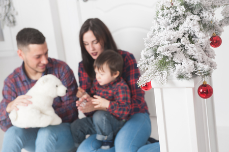 happy caucasian family man woman and kid with teddy polar bear in christmas eve decorationsの写真素材