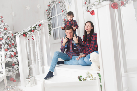 happy young caucasian family mother father kid sitting on porch of xmas decoration houseの写真素材