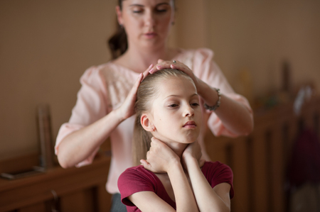 young beautiful caring mother fixing her dancer little thin daughter's hair before concert showの写真素材