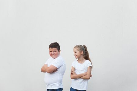 beautiful happy smiling fat boy and thin little girl in white shirt on bright background with copy spaceの写真素材