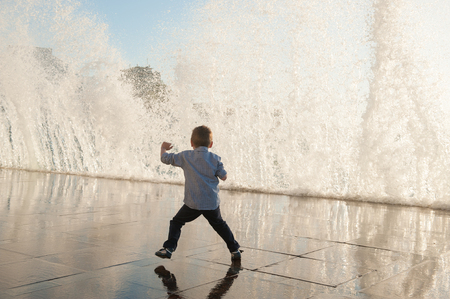one little kid escaping frome huge wave on sea shore in city during storm weatherの写真素材
