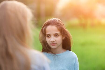 beautiful little girl with long hair looking at her friend with interestの写真素材