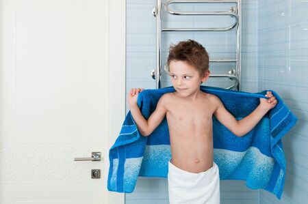 Healthy clean little boy with towels in blue bathroomの写真素材