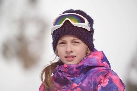 beautiful active smiling happy small young caucasian girl in woolen hat and snowboarding jacket with...