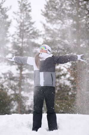 happy active small smiling little girl in winter sport clothes under flying snowの写真素材