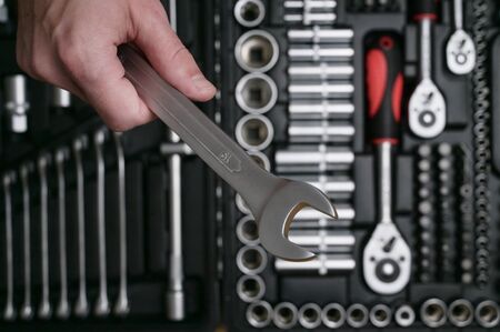 human hand holding chrome stainless car auto socket wrench on toolbox background