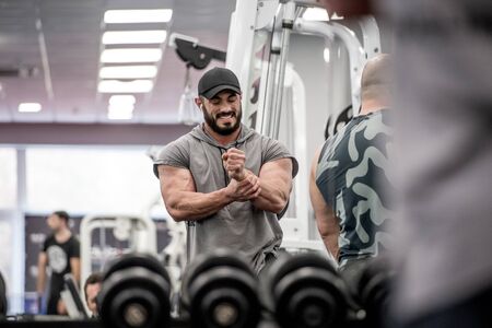 strong muscle bearded man holding his wrist with hand during sport training injury with grimace of pain on his face indoor gymの写真素材