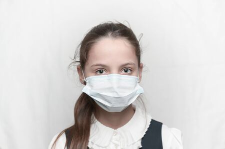 young beautiful little girl wearing medical mask and school uniformの写真素材