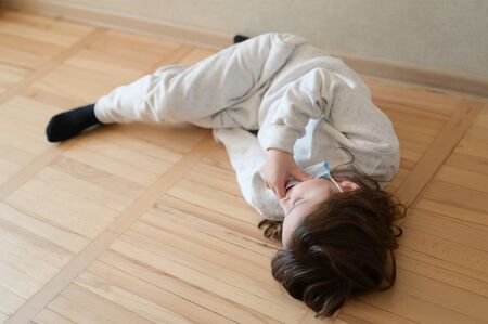 sick little girl lying at home wearing medical mask during world covid-19 coronavirus outbreakの写真素材