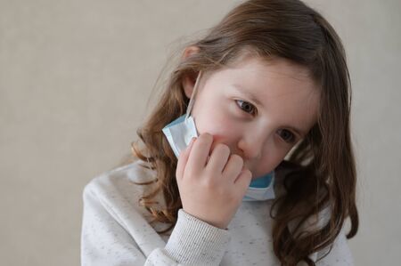 cute little sick sad girl in medical mask during virus epidemic outbreakの写真素材