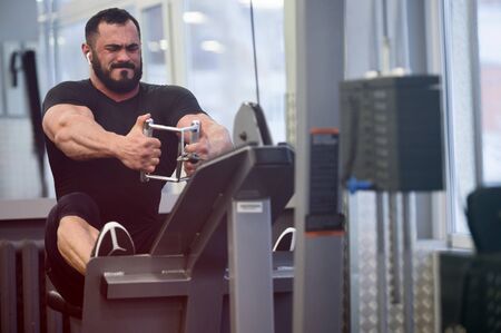 sport stress motivation of heavy workout in fitness gym by bearded young male in black jersey...
