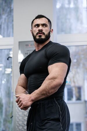 strong muscular young guy in black sport clothes indoors sport gymの写真素材