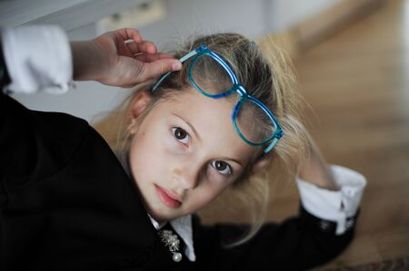 beautiful little girl in glasses and black and white dress lying at home during quarantine lockdownの写真素材