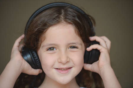stay at home during lockdown quarantine happy smiling small girl listening music in black headphonesの写真素材