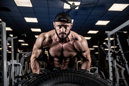 crossfit indoor gym training with truck tire of young handsome strong athlete male lifting heavy weightの写真素材