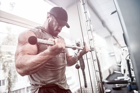 sport motivation concept of powerful focus bearded man training his biceps muscles in sport gymの写真素材