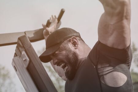 strong mighty athlete man with beard lifting heavy weight on sport fitness exercise equipment street...