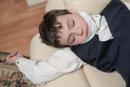 coronavirus covid-19 epidemic outbreak quarantine concept of small boy in medical mask lying at home being sick with high temperatureの写真素材