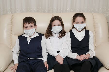school covid-19 virus quarantine family sick kids sitting at home in uniform wearing medical maskの写真素材