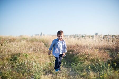 funny small active boy in shirt walking in outdoor summer nature fieldの写真素材