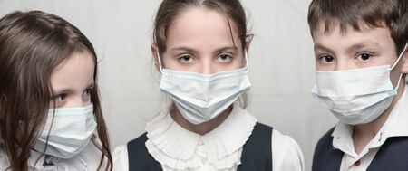 family of three little kids in medical masks and school uniform during coronavirus COVID-19 quarantineの写真素材
