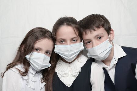 young family of three little kids in medical masks and school uniform during coronavirus COVID-19 epidemy quarantineの写真素材