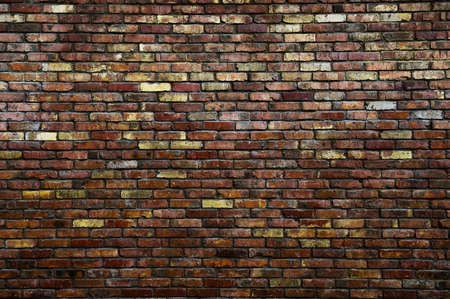 masonry concept of vintage aged brick wall of red and yellow color in urban darkness with copy spaceの写真素材