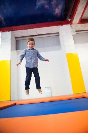 happy cute healthy little boy jumping on a trampoline indoorsの写真素材