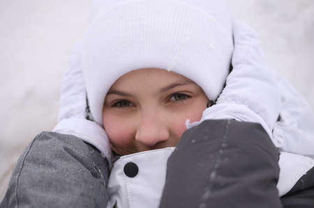 little caucasian girl with frozen ears in warm hat and gloves and jacket during winter travel holiday leisureの写真素材