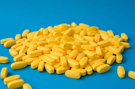 pharmacy industry production concept many yellow pills tablets on blue backgroundの写真素材