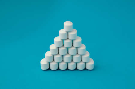 pharmacology medical concept pyramid of white pills tablets drugs on cyan surface with copyspaceの写真素材