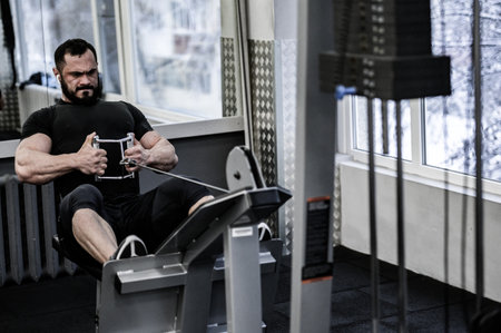 sport motivation workout concept of strong young man with beard lifting heavy weight in fitness gym...