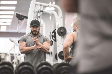 sport injury concept of young strong athlete bearded man holding his painful wrist with hand suffering from pain during training workout with peopleの写真素材