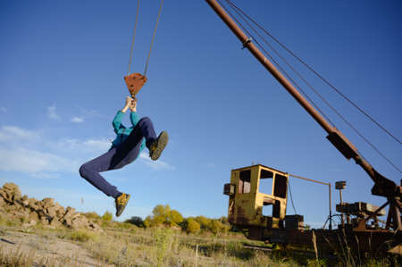 healthy one activre fun kid hanging on abandoned crane on old brick mine during outdoor leisure playful activityの写真素材