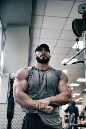 strong young caucasian male with beard showing strong muscles indoors gymの写真素材