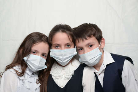 family of three little kids in medical masks and school uniformの写真素材